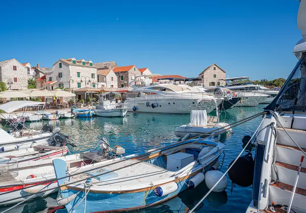 Birçok lüks yat ve tekne, sakin deniz ve uzak yeşil kıyı şeridi ile çevrili güneşli bir marinada demirlemiştir.