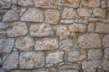 Görünür harç eklemleri, arka plan veya doku kullanımı için ideal, çeşitli boyutlarda ve doğal kayaların gölgelerini gösteren, dokulu taş bir duvarın kırsal, tam çerçeve yakın çekimi.