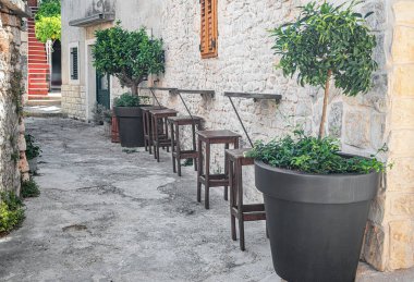 Samimi bir açık hava bar kurulumunda ahşap tabureler ve kır taşından bir duvar boyunca küçük masalar, saksı ağaçları ve yeşilliklerle süslenmiş, büyüleyici bir Akdeniz atmosferini çağrıştırıyor..
