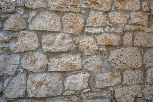 Görünür harç eklemleri, arka plan veya doku kullanımı için ideal, çeşitli boyutlarda ve doğal kayaların gölgelerini gösteren, dokulu taş bir duvarın kırsal, tam çerçeve yakın çekimi.