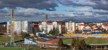 Panoramik manzara, Ukrayna 'nın Ukrayna' nın Uzhhorod kentinin renkli çatıları yamaçlardan aşağı dökülüyor, dramatik bulutlu bir gökyüzüne ve uzak dağlara karşı kuruluyor.