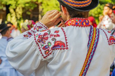 Canlı bir açık hava kültür festivali sırasında karmaşık nakış işlemeli renkli geleneksel Doğu Avrupa halk kıyafetleri giyiliyor.