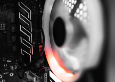 Karmaşık kablolar ve kırmızı-turuncu RGB ışıklandırmasıyla aydınlatılan parlayan bir soğutma vantilatörü içeren bilgisayar iç bileşenlerinin yakın plan görüntüsü.