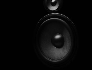Woofer ve tweeter sürücüleri ile siyah ses hoparlörü koyu bir arka planda izole edilmiş, profesyonel ses sistemi tasarımını vurguluyor.