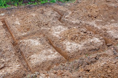 Bir inşaat temeli için çukur kazılmış kahverengi toprak, yukarıdan bakıldığında.