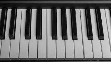 Karanlığın içinden yükselen bir piyano klavyesinin yüksek kontrastlı, karamsar çekimi, tuşları vurguluyor..