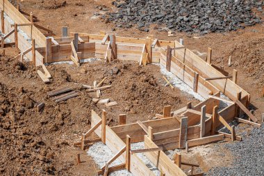 İnşaat alanındaki toprak ve çakıllarla çevrili ahşap bir yapı üzerine beton bir temel dökülüyor..