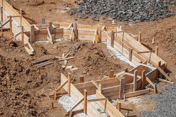 İnşaat alanındaki toprak ve çakıllarla çevrili ahşap bir yapı üzerine beton bir temel dökülüyor..