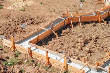 Taze betonla dolu ahşap işlemeli bir bina inşaatın erken safhalarında bir inşaat sahasında gösteriliyor.