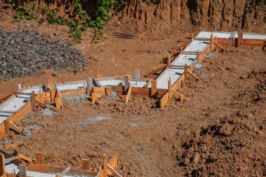 Taze betonla dolu ahşap işlemeli bir bina inşaatın erken safhalarında bir inşaat sahasında gösteriliyor.