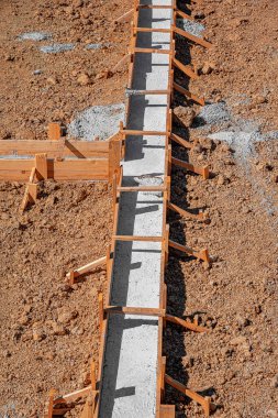 Taze betonla dolu ahşap işlemeli bir bina inşaatın erken safhalarında bir inşaat sahasında gösteriliyor.