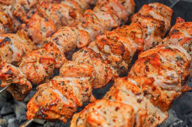 Sulu marine edilmiş şişler, açık hava barbeküsü sırasında metal şişler üzerinde kızgın kömür üstünde kızartılıyor..