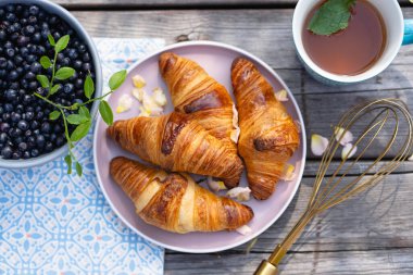 Güneşli bir piknikte taze pişmiş yaban mersinli kruvasan ve nane çayı.