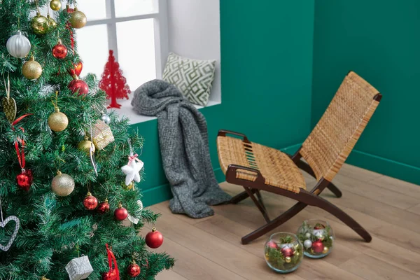 Green corner room style, close up Christmas and new year tree, ornament, accessory, windows, blanket and wooden chair style.