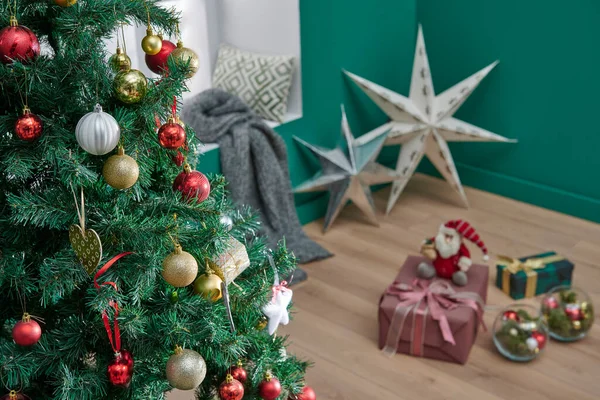 Green corner room style, close up Christmas and new year tree, ornament, accessory, windows, blanket and wooden chair style.