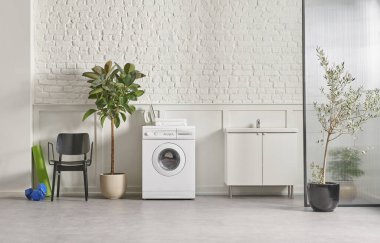 Washing machine in the bathroom, white brick wall background, vase of plant, cabinet and marble floor, folding screen.