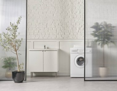 Washing machine in the bathroom, white brick wall background, vase of plant, cabinet and marble floor, folding screen.