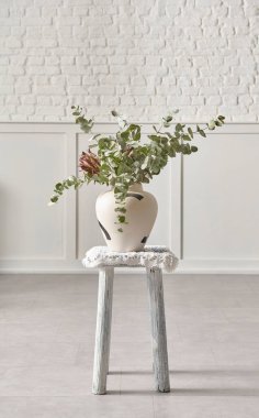 Vase of plant and flower style on the chair, white wall background.