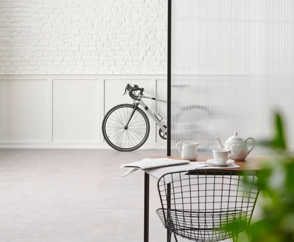 Bike in the room, chair table desk white brick and classic wall, blur green leaf.