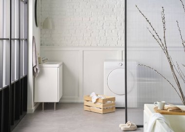 Beyaz banyo, çamaşır ve kuru makine, tuğla duvar ve şeffaf ekran, dolap lavabo ve ayna, bitki.