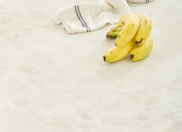 Bananas are on the grey concrete table, close up, white and blue napkin background.