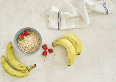 Fincanda muz ve granola, gri arka plan manzaralı..