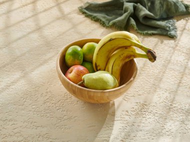 Tabakta çeşitli meyveler ve ahşap masada bir fincan. Muz, elma, armut ve mandalina..