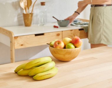 Ahşap masanın, mutfağın, muzun, elmanın ve armutun üzerindeki meyve sepetini kapat. Kadın arkaplan biçimi.