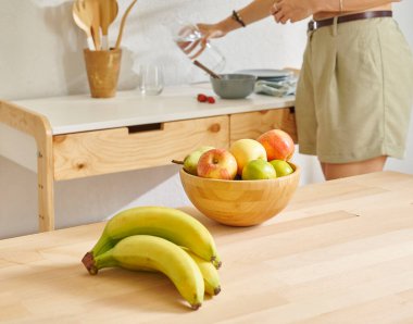 Ahşap masanın, mutfağın, muzun, elmanın ve armutun üzerindeki meyve sepetini kapat. Kadın arkaplan biçimi.