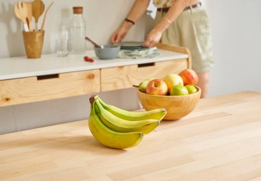 Ahşap masanın, mutfağın, muzun, elmanın ve armutun üzerindeki meyve sepetini kapat. Kadın arkaplan biçimi.