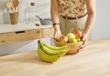 Ahşap masanın, mutfağın, muzun, elmanın ve armutun üzerindeki meyve sepetini kapat. Kadın arkaplan biçimi.