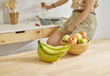 Ahşap masanın, mutfağın, muzun, elmanın ve armutun üzerindeki meyve sepetini kapat. Kadın arkaplan biçimi.