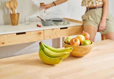 Ahşap masanın, mutfağın, muzun, elmanın ve armutun üzerindeki meyve sepetini kapat. Kadın arkaplan biçimi.