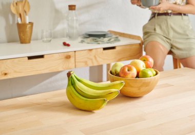 Ahşap masanın, mutfağın, muzun, elmanın ve armutun üzerindeki meyve sepetini kapat. Kadın arkaplan biçimi.