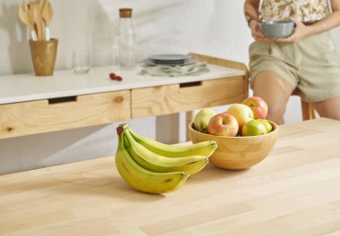 Ahşap masanın, mutfağın, muzun, elmanın ve armutun üzerindeki meyve sepetini kapat. Kadın arkaplan biçimi.