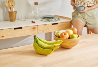 Ahşap masanın, mutfağın, muzun, elmanın ve armutun üzerindeki meyve sepetini kapat. Kadın arkaplan biçimi.