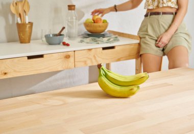 Ahşap masada muz ve mutfak tarzı. Kadın arkaplanı.