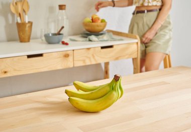 Ahşap masada muz ve mutfak tarzı. Kadın arkaplanı.