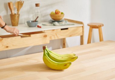 Ahşap masada muz ve mutfak arka planında.
