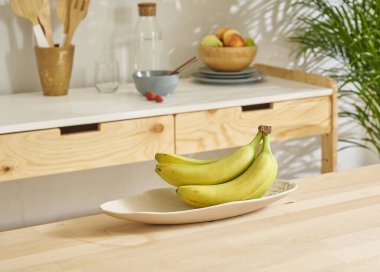 Ahşap masada muz ve mutfak arka planında.