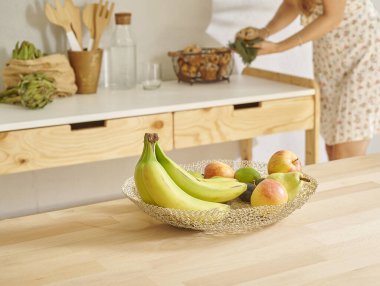 Muz ve sepette çeşitli meyveler, dekoratif ahşap mutfak içi. Kadın arkaplanı.