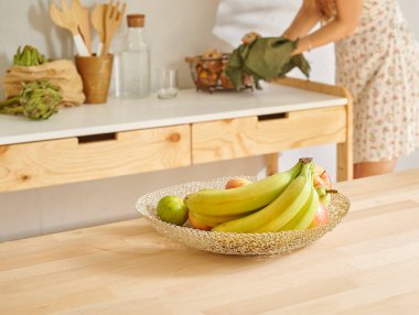 Muz ve sepette çeşitli meyveler, dekoratif ahşap mutfak içi. Kadın arkaplanı.