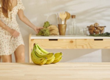 Ahşap masada muz ve mutfak tarzı. Kadın arkaplanı.