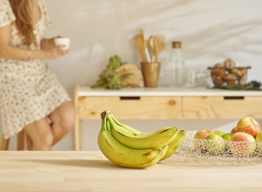 Muz ve sepette çeşitli meyveler, dekoratif ahşap mutfak içi. Kadın arkaplanı.