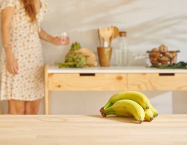 Ahşap masada muz ve mutfak tarzı. Kadın arkaplanı.