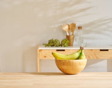 Ahşap masada muz ve mutfak arka planında.