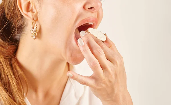 Woman eating biscuit, close-up, mouth and hand. Kitchen background style.