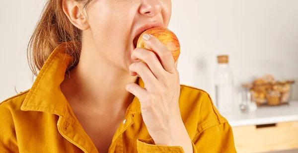 Egy Almát Eszik Közelről Kézzel Szájjal Konyhai Háttér — Stock Fotó
