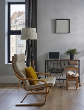 Dekoratif oda koltuğu, masa, dizüstü bilgisayar, vazo, lamba ve çerçeve gri duvarın önünde, kahverengi perde, parke iç tasarım, çalışan köşe.