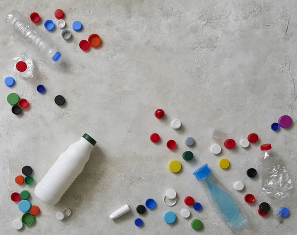 Plastic bottles and caps are on the green table, recycling waste concept.